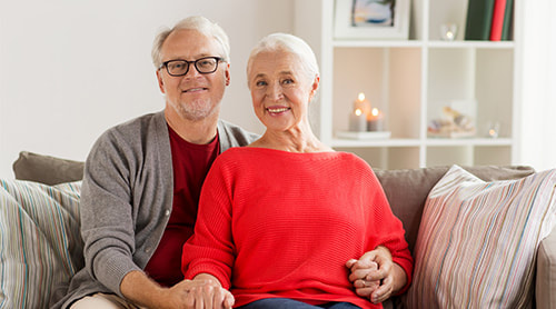 Smiling elder couple sitting in the sofa photo